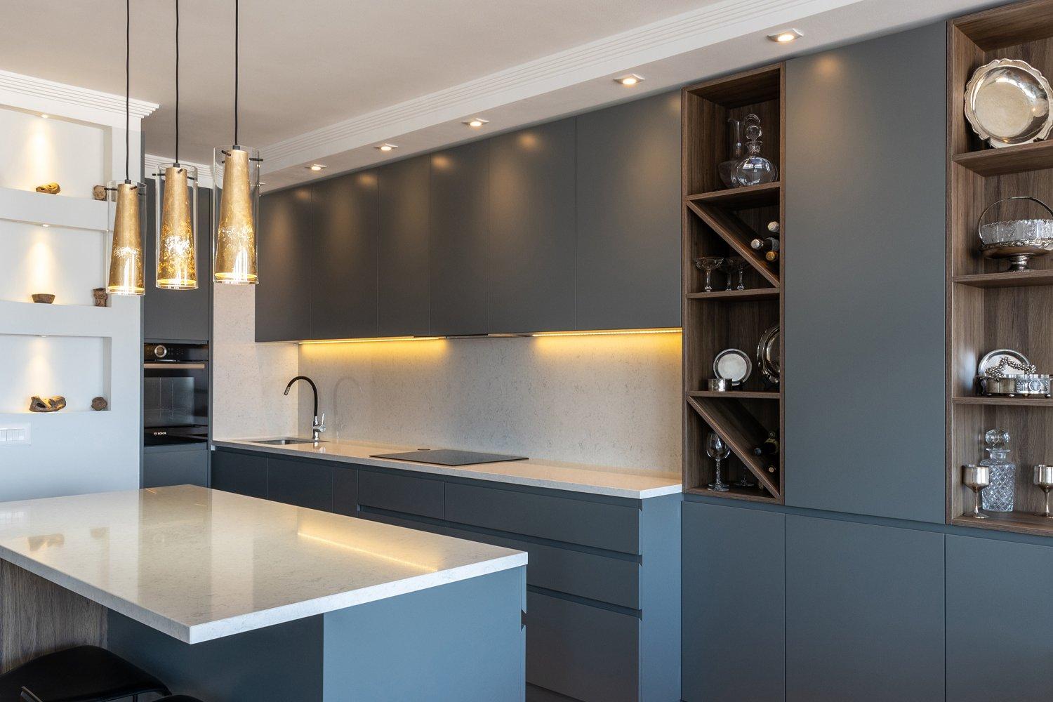Modern, streamlined kitchen featuring dark gray cabinets and white countertops